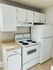 Cozy kitchen featuring white cabinets, a stove, and a refrigerator.