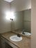 Modern bathroom with sleek vanity and large mirror featuring warm lighting.