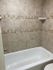 Chic bathroom with textured tile walls and a pristine white bathtub.