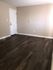 Bright room with dark wood flooring and a white door, highlighting minimalist design.