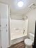Elegant modern bathroom featuring a sleek shower-tub combo, bright lighting, and sleek cabinetry.