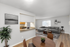 Stylish open-plan living room with modern gray sofa, dining area, and kitchen view.