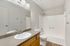 Modern bathroom featuring a sleek countertop, bright lighting, and a spacious shower.
