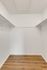 Bright, airy walk-in closet with wooden flooring and white walls equipped with dual hanging rods.