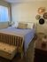 Inviting bedroom with a plush bed, side table, and decorative hats on the wall.