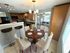 Chic dining area with round wooden table, stylish chairs, and modern kitchen overlooking living space.