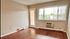 Spacious living room with wooden flooring, large window, and natural light.