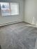 Inviting bedroom space with soft carpet and large window allowing natural light.