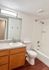 Bright bathroom featuring a contemporary sink, elegant vanity, and a sleek bathtub with a shower.