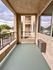 Inviting apartment balcony with green floor, overlooking a serene neighborhood street.