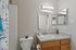 Contemporary bathroom with sleek vanity, large mirror, and bright lighting.