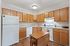 Bright kitchen with wooden cabinets, white appliances, and a central dining table.