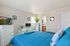 Inviting bedroom with vibrant blue bedding, elegant decor, and a spacious layout.
