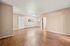 Spacious open-concept room with wooden floors and neutral walls, featuring a large window and a door.