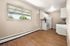 Inviting kitchen area with modern appliances and wooden flooring, accented by a large window overlooking greenery.