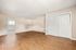 Bright and open living room with wooden flooring and neutral walls, featuring a large closet and ample natural light.
