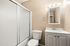 Elegant bathroom featuring a white vanity, sleek mirror with lights, and a sliding glass shower door.