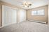 Spacious bedroom featuring beige walls, carpeted flooring, and double closets with paneled doors.