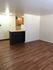 Open-concept apartment with stylish wooden flooring and modern kitchen with bar counter.
