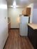 A cozy kitchen with wooden cabinetry, white appliances, and elegant brown flooring.