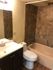 Cozy bathroom with tan tile walls, a classy white vanity, and a bathtub.