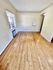Bright room with polished hardwood floors and a large window, offering ample natural light.