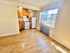 Bright kitchen with wooden cabinets, white appliances, large window, and natural hardwood floors.