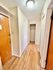Warm and welcoming apartment entryway with wooden flooring and ample lighting.