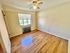 Bright and airy bedroom with hardwood floors and a ceiling fan, featuring a large window bringing in natural light.