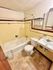 Modern bathroom with a bathtub, toilet, and wall-mounted sink featuring elegant tile work.