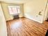 Bright room with natural wood flooring, large window, and neutral walls, ideal for a cozy living space.