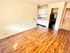 Compact kitchen space with modern cabinets and fridge, set against hardwood flooring and neutral walls.
