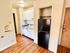 Cozy kitchen with white cabinetry, black refrigerator, and wood flooring.