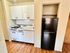 Sleek white kitchen with modern cabinets, compact stove, and black refrigerator.
