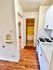 Inviting kitchen featuring white cabinetry and wood flooring leading to a hallway with open doorways.