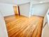 Elegant living space with polished hardwood floors and a view into a cozy kitchen.