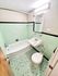 Stylishly renovated bathroom with mint green tiling, modern fixtures, and a classic white bathtub.