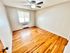 Inviting bedroom with polished hardwood floors, a large window, and a ceiling fan.