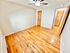 Bright and spacious bedroom with polished hardwood floors, wooden doors, and a ceiling fan.