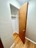 Open closet with wooden door and shelving on hardwood floors.