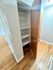 Wooden floor hallway with an open closet door revealing multiple shelves.