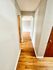Bright hallway featuring wooden floors and pristine white walls.
