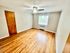 Spacious room with hardwood flooring and natural light from a window, featuring a ceiling fan.