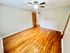 Bright room with polished hardwood floors, ceiling fan, and neutral walls.