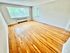 Sunlit room with large windows and polished hardwood floors.