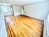 Bright apartment living room with gleaming hardwood floors and large windows.