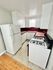 Bright kitchen with white cabinetry, red tile backsplash, and modern appliances.