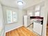 Charming kitchen with white cabinets, red backsplash tiles, and natural light streaming through a window.