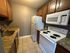 Compact kitchen with granite countertops, white appliances, and wood cabinetry.