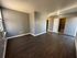 Bright and airy living room area with hardwood floors and gray walls, leading to an open doorway.